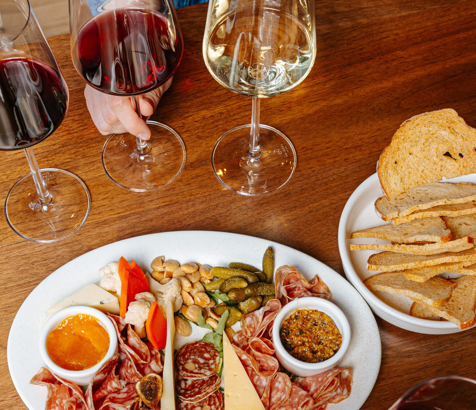 Glasses of wine next to cheese and charcuterie plate
